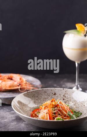 Funchose Salat mit Garnelen und Gemüse mit Sesamsamen und Cocktailglas. Foto für Menü Stockfoto