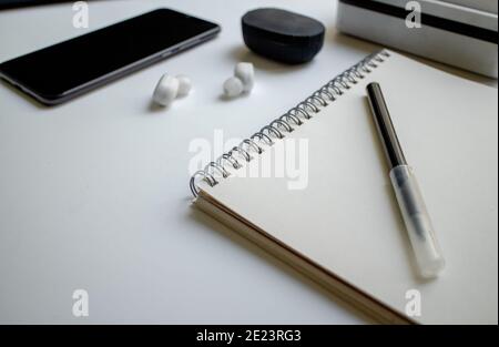 Notizblock für Notizen an den Ringen und ein schwarzer Filzstift. Arbeitsplatz im Büro. Mobiltelefon mit Kopfhörern. Geschäftsideen und Kreativität. Stockfoto