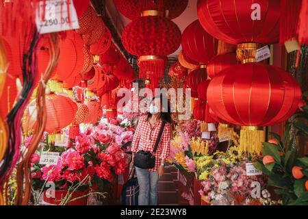 Kuala Lumpur, Malaysia. Januar 2021. Eine malaysische ethnische Chinesin, die eine Gesichtsmaske als vorbeugende Maßnahme gegen die Ausbreitung des Coronavirus (Covid-19) trägt, durchstösst in einem Geschäft die Lunar New Year Laternen. Da die kovid19 Fälle in Malaysia sprunghaften, wird die Movement Control Order (MCO) in sechs Staaten wieder eingeführt, während sechs weitere unter der von Premierminister Tan Sri Muhyiddin Yassin angekündigten bedingten Movement Control Order (CMCO) von Januar 13 bis Januar 26 bleiben werden. Kredit: SOPA Images Limited/Alamy Live Nachrichten Stockfoto