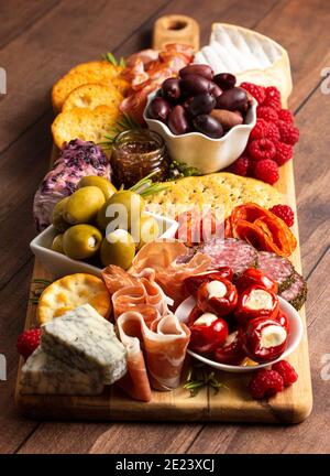 Bohnenkraut Wurstwaren Board in Fleisch Oliven Paprika Beeren und bedeckt Käse Stockfoto