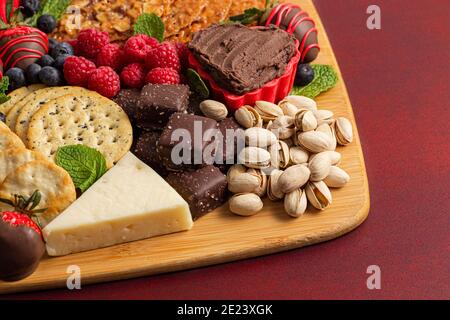 Schokolade überzogene Erdbeeren und Käse Süße Wurstplatte auf einem Roter Tisch Stockfoto