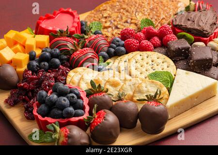 Schokolade überzogene Erdbeeren und Käse Süße Wurstplatte auf einem Roter Tisch Stockfoto