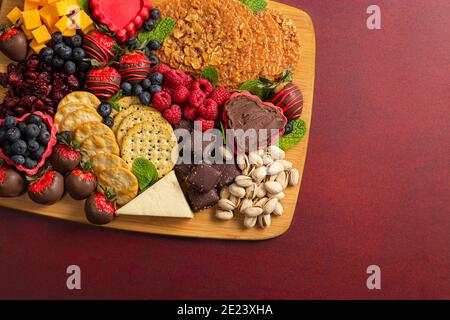 Schokolade überzogene Erdbeeren und Käse Süße Wurstplatte auf einem Roter Tisch Stockfoto