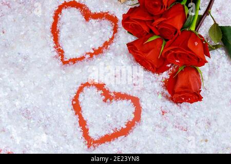 Herzformen auf funkelndem Schnee und schönen roten Rosen. Muttertag oder Valentinstag. Stockfoto