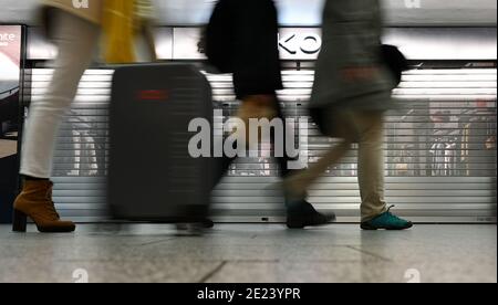 08. Januar 2021, Hessen, Frankfurt/Main: Flugreisende gehen an den geschlossenen Geschäften im Terminal 1 des Frankfurter Flughafens vorbei. Die Corona-Krise zeigt sich besonders an Deutschlands größtem Drehkreuz. Mit nur gut 400 Flugbewegungen und rund 22,000 Passagieren pro Tag hat der Flughafen ein sehr niedriges Niveau erreicht. (To dpa 'Weltflughafen im Winterschlaf - Mitarbeiter fürchten um Arbeitsplätze') Foto: Arne Dedert/dpa Stockfoto