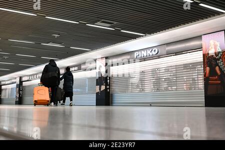 08. Januar 2021, Hessen, Frankfurt/Main: Flugreisende gehen an den geschlossenen Geschäften im Terminal 1 des Frankfurter Flughafens vorbei. Die Corona-Krise zeigt sich besonders an Deutschlands größtem Drehkreuz. Mit nur gut 400 Flugbewegungen und rund 22,000 Passagieren pro Tag hat der Flughafen ein sehr niedriges Niveau erreicht. (To dpa 'Weltflughafen im Winterschlaf - Mitarbeiter fürchten um Arbeitsplätze') Foto: Arne Dedert/dpa Stockfoto