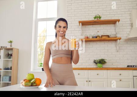 Glückliche junge Fitness Frau athet in Sportbekleidung stehen und trinken Frischer Orangensaft Stockfoto
