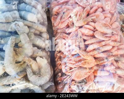 Zwei große Plastiktüten mit gefrorenen rohen und gekochten Garnelen, auf der Theke des Fischmarktes. Stockfoto