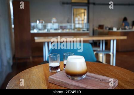 Nahaufnahme Glas Tasse Nitro kalt brauen Kaffee auf Holz Tablett Tisch, schwarzer Kaffee langsam mit Stickstoff Gas infundieren Stockfoto