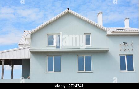 Eine hellblaue und weiße Haus Stuckfassade, Dachfenster, Außenwand Renovierung und Rendering, offene Balkon Rekonstruktion mit einer Klimaanlage. Stockfoto