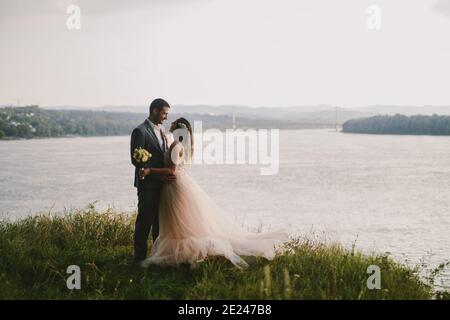 Emotionales Bild von gerade verheirateten Paar im Feld stehen und küssen. Fluss im Hintergrund.Paar Ziele. Stockfoto