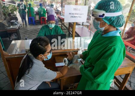Denpasar, Indonesien. Januar 2021. Ein Gesundheitspersonal, das einen Schutzanzug trug, sah, wie eine Frau vor der Impfung gesichtet wurde.das Public Health Centre (Puskesmas) IV von South Denpasar hielt vor dem nationalen Tag der gleichzeitigen Impfung, der vom 14. Dezember 2020 beginnen wird, die Impfungssimulation Covid-19. Kredit: Dicky Bisinglasi/SOPA Images/ZUMA Wire/Alamy Live Nachrichten Stockfoto
