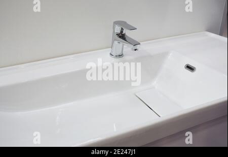 Eine Nahaufnahme eines weißen Porzellan Keramik flachen Rechteck Wand montiert Waschbecken, Waschbecken mit einer rechten Seite Chrom Wasserhahn in einem weißen Badezimmer Stockfoto