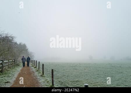 Zwei Wanderer gehen den Jurassic Way Pfad neben East Carlton Park, Corby, Nhants, England, an einem nebligen januartag während der 2021 Sperre Stockfoto