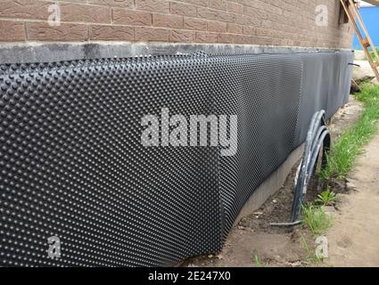 Schutz des Kellerfundaments außerhalb eines Ziegelhauses vor Wasser und Feuchtigkeit mit einem Fundament Abdichtung Grübchen Membran, Barriere. Stockfoto