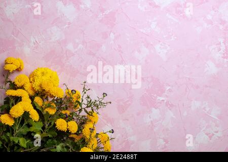 Nachbildung eines Straußes aus gelben Astern und Chrysanthemen Auf einem rosa Betongrund Stockfoto