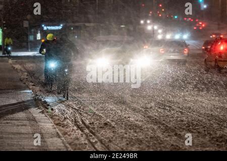 12. Januar 2021, Hessen, Frankfurt/Main: Radfahrer und Autofahrer sind in der morgendlichen Hauptverkehrszeit auf der verschneiten Alten Brücke über den Main. In Hessen ist mit rutschigen Straßen auch in tiefen Höhenlagen zu rechnen. Foto: Frank Rumpenhorst/dpa Stockfoto