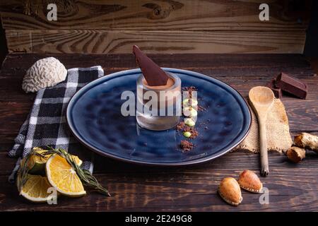 Servieren von köstlichen Schokoladenmousse in einem Glas mit einem Ein Stück Schokolade auf einem blauen Teller Stockfoto