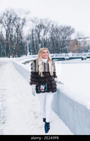 Lächelnde Frau in Pelz getragen Spaziergänge im Winter verschneit parken Stockfoto