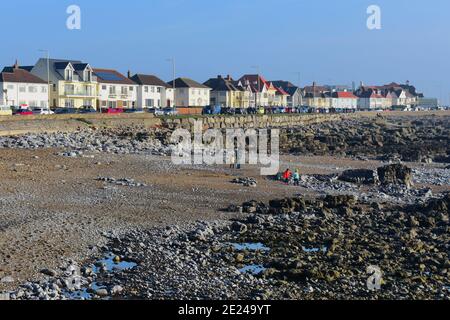 Die Promenade in Porthcawl mit Häusern mit Blick auf das Meer. Bei Ebbe wird das felsige Vorland mit nur einem kleinen Sandbereich aufgedeckt. Stockfoto