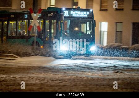 12. Januar 2021, Hessen, Frankfurt/Main: Ein Bus mit wenigen Fahrgästen ist in der Friedberger Landstraße während der morgendlichen Hauptverkehrszeit im Schnee unterwegs. In Hessen ist auch in tiefen Höhenlagen mit rutschigen Straßen zu rechnen. Foto: Frank Rumpenhorst/dpa Stockfoto