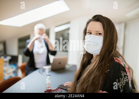 Frau im Büro trägt Gesichtsmaske Stockfoto