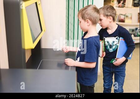 Jungen, die einen Self-Service-Punkt in der Bibliothek benutzen Stockfoto