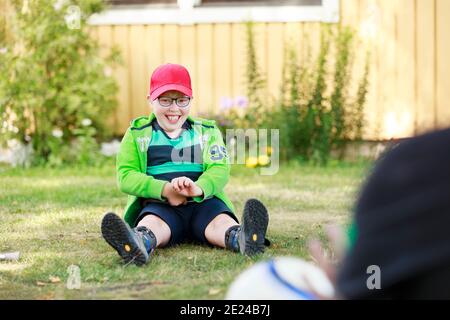 Glücklicher Junge im Garten sitzen Stockfoto