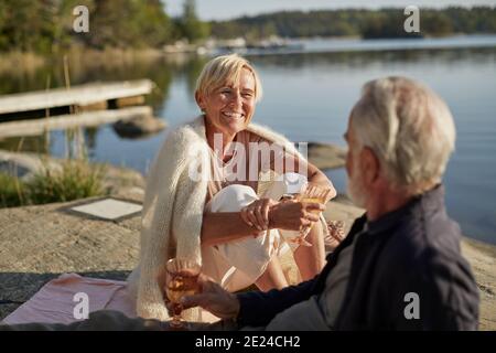 Lächelndes Paar beim Picknick am See Stockfoto