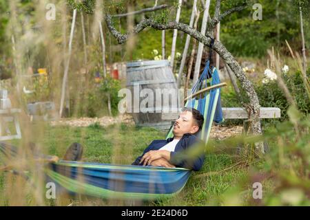 Mann im Garten, der sich in der Hängematte entspannt Stockfoto