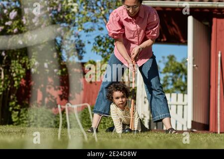 Mutter mit Kleinkind spielt Krocket im Garten Stockfoto