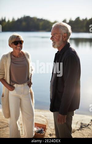 Lächelndes Paar, das am See steht Stockfoto