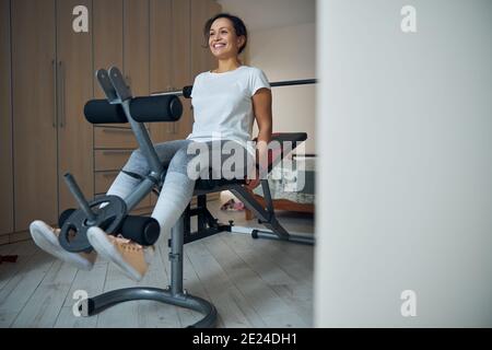 Fröhliche niedliche Sportlerin Durchführung der sitzenden Bein curl Stockfoto