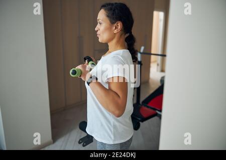 Athletische Frau, die eine Armübung innen durchführt Stockfoto