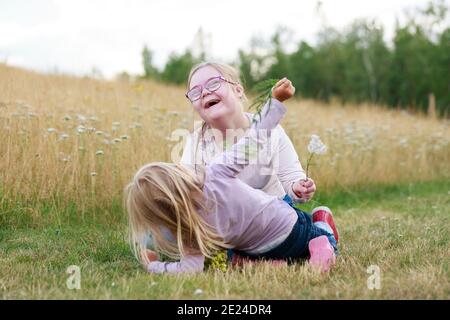 Glückliche Schwestern spielen auf der Wiese Stockfoto