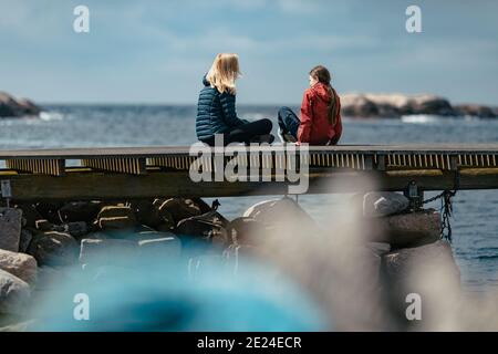 Mutter und Tochter sitzen auf dem Steg Stockfoto