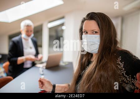 Frau im Büro trägt Gesichtsmaske Stockfoto