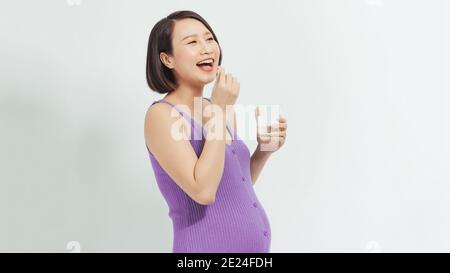 Schwangere Frau hält Vitaminpille und ein Glas Wasser Stockfoto