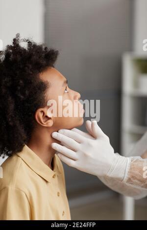 Vertikale Seitenansicht Nahaufnahme von nicht erkennbaren Arzt untersucht Junge für Covid während der Konsultation in der Klinik Stockfoto