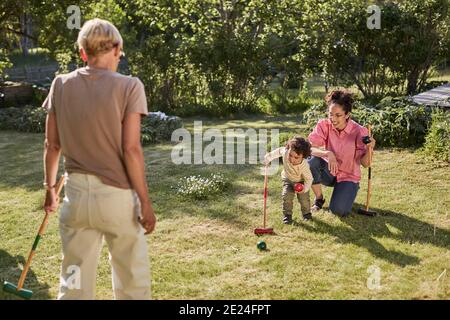 Mutter mit Kleinkind spielt Krocket im Garten Stockfoto