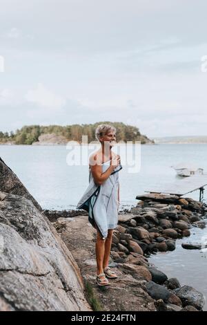 Lächelnde Frau in Handtuch auf See gewickelt Stockfoto