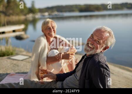 Lächelndes Paar beim Picknick am See Stockfoto