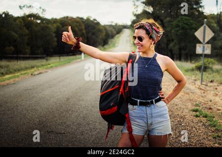 Unabhängige Frau auf einem Roadtrip, allein mit dem Anhalter unterwegs. Rucksackreisen sind eine Reise mit geringem Budget. Stockfoto