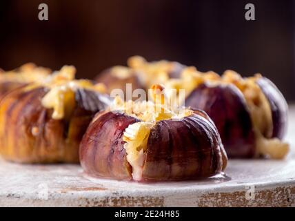 Reife Feigen gebacken mit Kuhmilchkäse Brie und Camambert und bestreut mit Semmelbröseln mit Minzblättern verziert. Gesunde Ernährung Konzept. Nahaufnahme Stockfoto