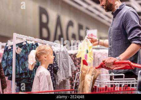 Vater mit Tochter, die Kleidung im Supermarkt ansieht Stockfoto