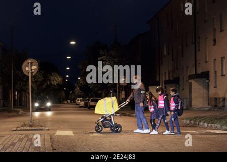 Vater mit Kindern überqueren Straße am Abend Stockfoto