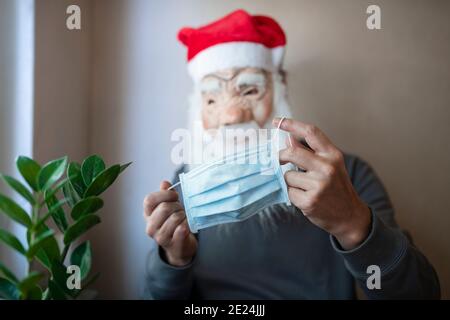 Mann trägt Santa Maske hält Gesichtsmaske Stockfoto