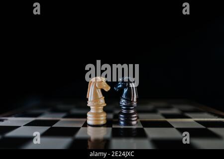 Zwei Pferde-Stücke einander gegenübergestellt auf einem Schachbrett in einem dunklen Stil. Interracial Liebe Konzept. Selektiver Fokus Stockfoto