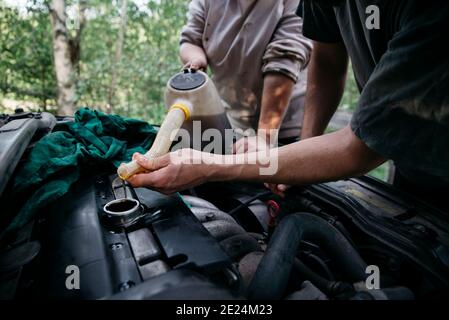 Menschen, die Öl in den Motor gießen Stockfoto