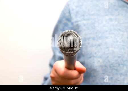 Ein Mann hält ein silbernes Mikrofon in der Hand und führt Geschäftsinterviews, journalistische Berichterstattung, Public Speaking, Pressekonferenz, Karaoke Stockfoto